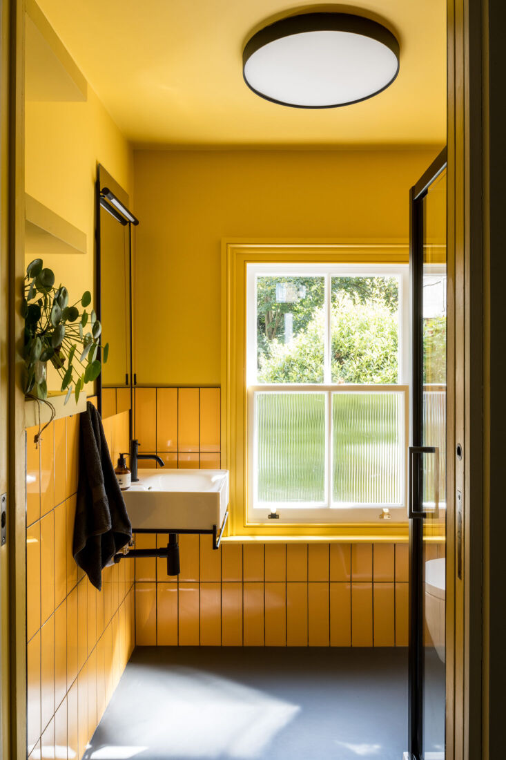 the bathroom is anchored by electric yellow tile set with black grout. photogra 18
