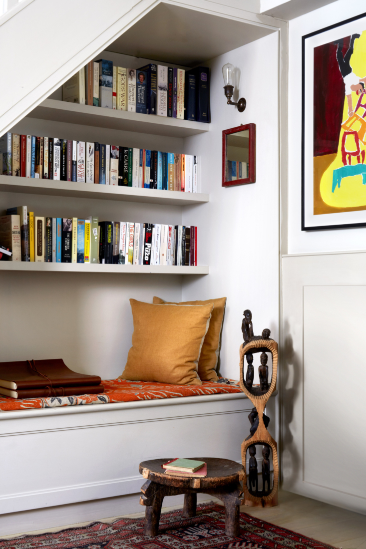 the nook under the stair has a window seat with storage. the african carvings a 19