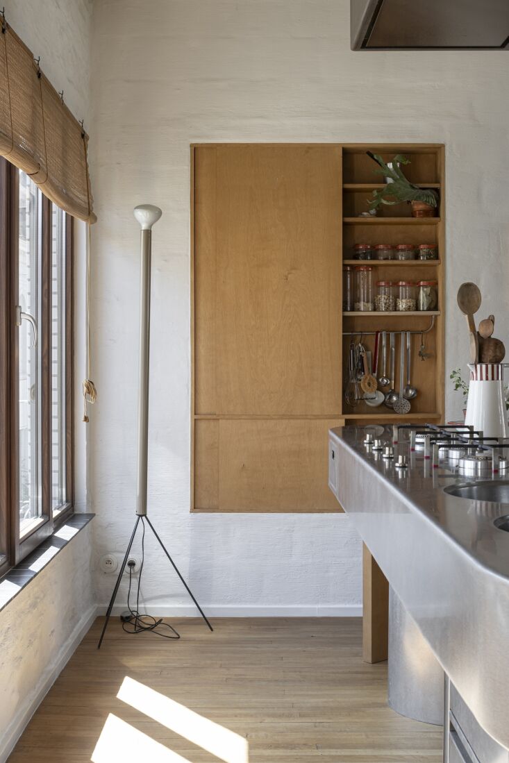 kitchen tools hang from a rod in the built in cupboard. the tripod light is ach 27