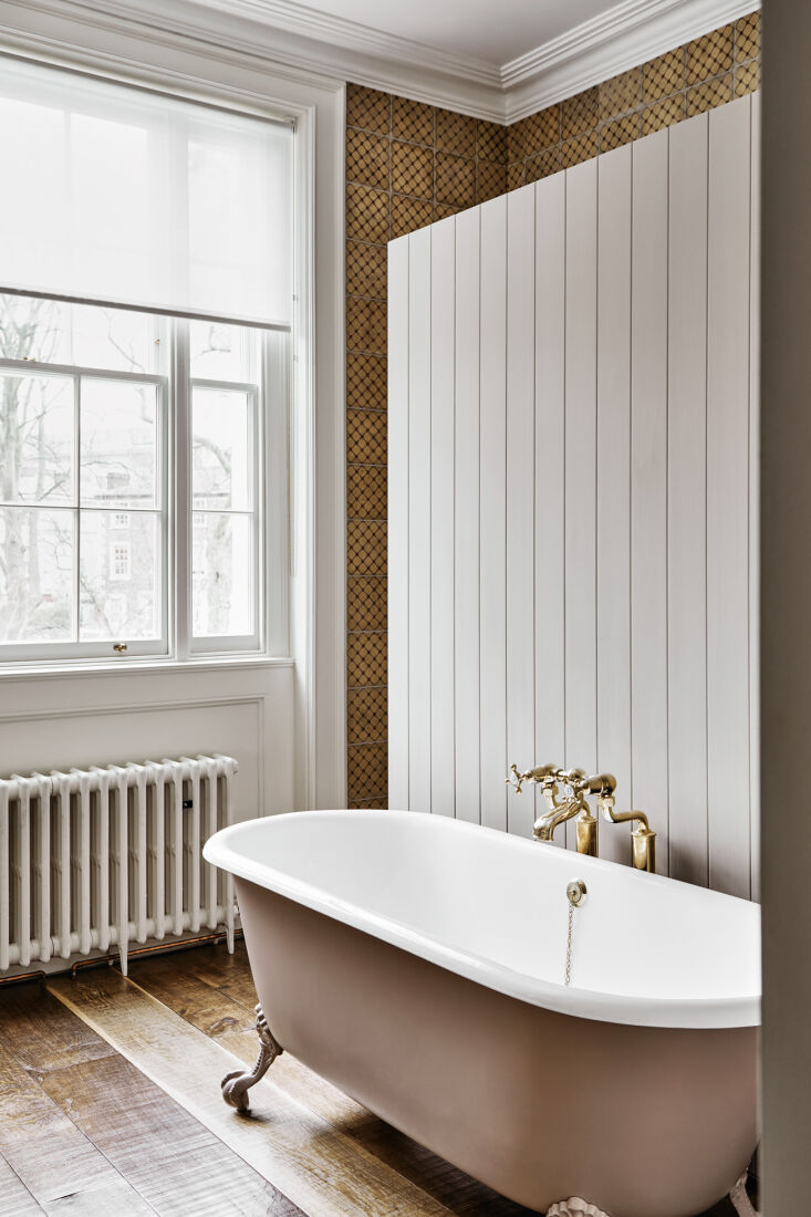 a paneled divider sets off a clawfoot bathtub from drummonds, another uk compan 37