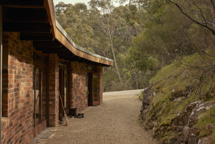 the unassuming home is nestled between a hillside and a cliff that drops down t 17