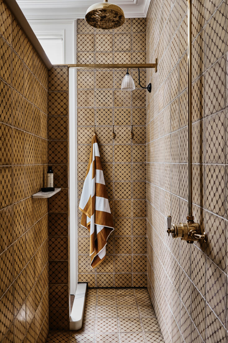 the shower has a carrara marble step and shelves. the brass shower fixture is f 38
